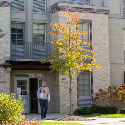 Goodenough Hall in the autumn with a student on his way to class